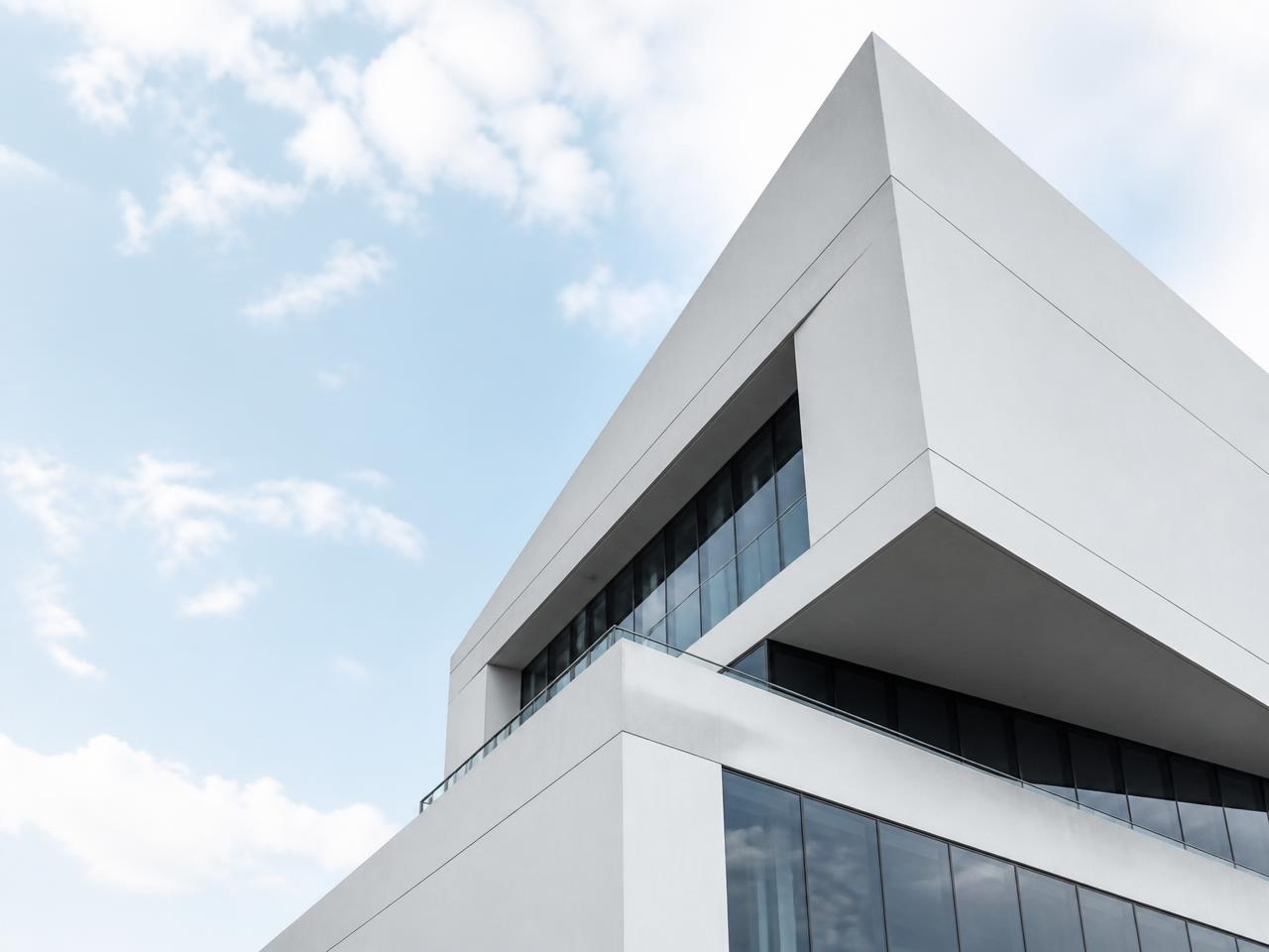 Modern white concrete building facade against a bright sky